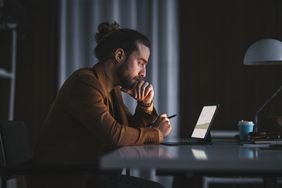 一个男人晚上在家里看着他的平板电脑上的共同基金投资