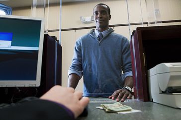 一名男子站在银行出纳处用现金支付一张汇款单
