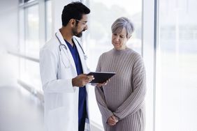 医生和病人在谈话，看着电子平板电脑。