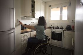 坐在轮椅上的女人按着厨房墙上的按钮
