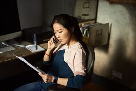 一位神情严肃的女士拿着税务文件打电话