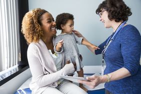 一名医生向一名儿童病人和病人的母亲打招呼。
