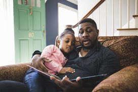 Parent and child read a book together at home.