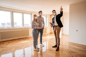 在冠状病毒大流行期间，房地产经纪人在向一对夫妇展示新公寓时与他们交谈。