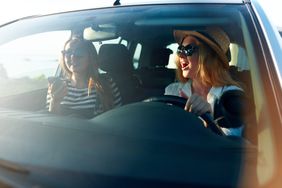 两个微笑的年轻女人戴着墨镜在车里