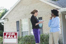 一个房地产经纪人站在一个挂着出售标志的房子前，和另一个女人交谈＂>
          </noscript>
         </div>
        </div>
       </div>
       <div class=
