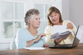 成熟的女人(60岁)帮助年长的母亲(90岁)支付账单。