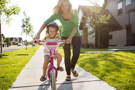 妈妈帮女儿骑自行车”width=