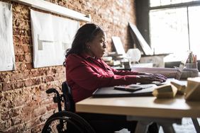 坐在轮椅上用笔记本电脑工作的女人