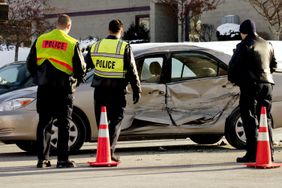 警察和一名司机在车祸现场驾驶一辆损坏的银色汽车