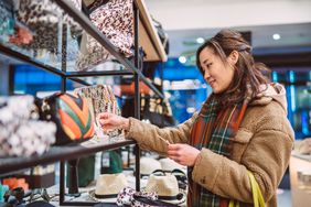 一名穿着冬季大衣、戴着围巾的女子在商店里看着货架上的商品