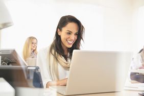 微笑的女人在办公室使用笔记本电脑