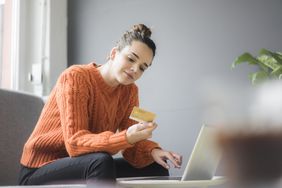 Person on couch using laptop and credit card