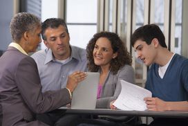 父母和儿子与财务顾问谈论大学费用借款。”width=