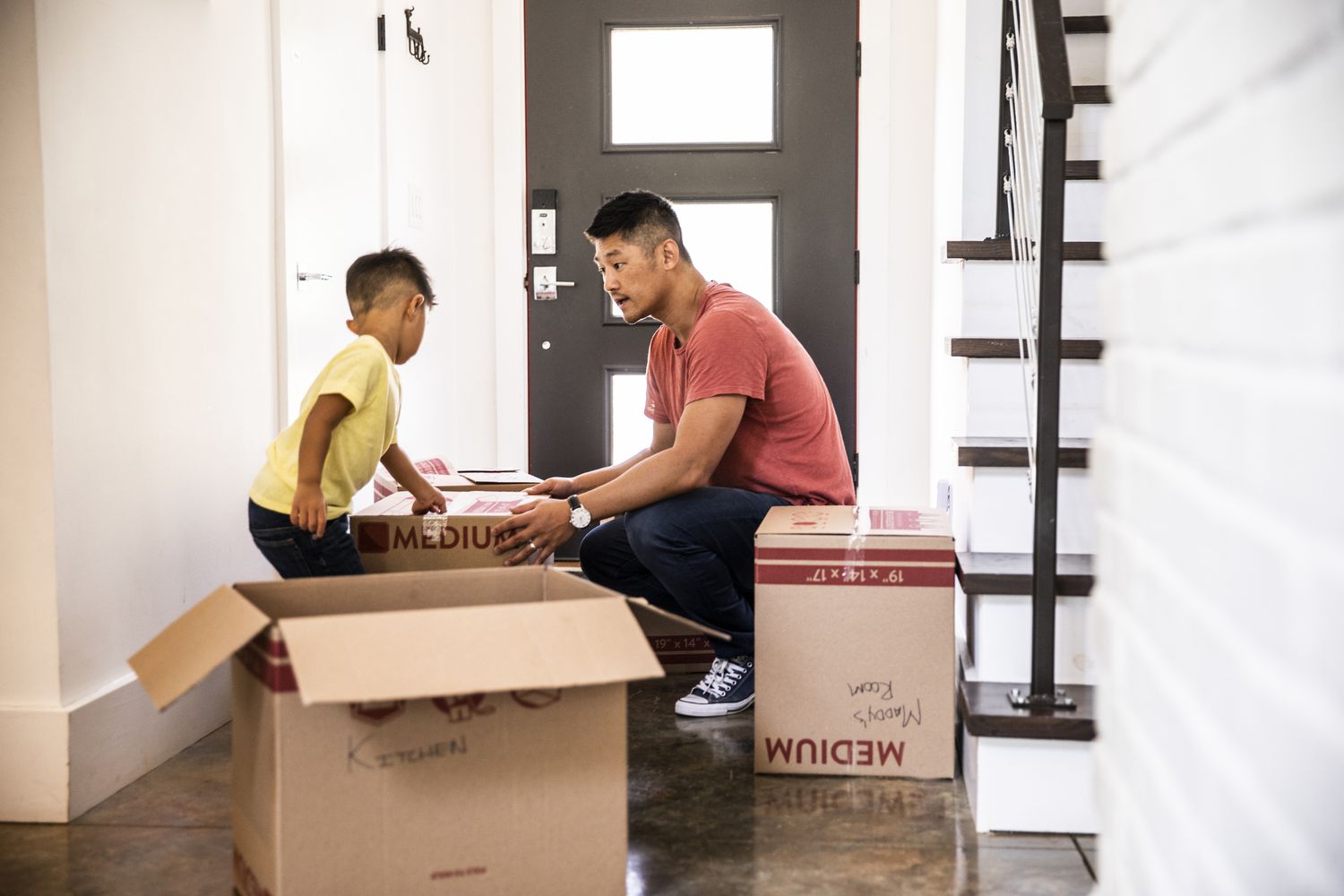 一个男人和一个小男孩搬箱子到一个空房子里。