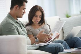 一对年轻夫妇在审查他们的财务预算，以确定他们是否可以坐在沙发上靠一份收入生活