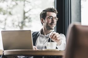 投资者一边喝着咖啡，一边在电脑前思考他的科技共同基金。