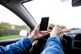 人使用智能手机同时开车。