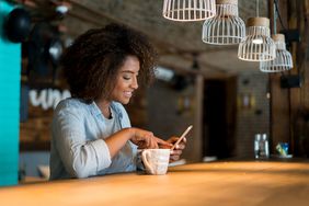 一个人在咖啡馆边喝咖啡边用手机看社交媒体