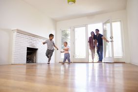 two kids running into an empty house. two adults are behind them, coming through the door.