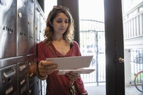 一名年轻女子在公寓的邮箱前整理她收到的邮件