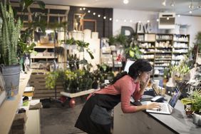 女店主在植物店柜台用手提电脑打电话