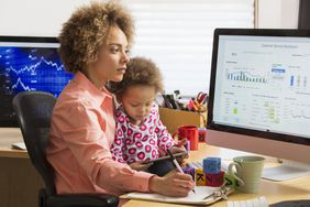 膝上抱着孩子的妇女在电脑上比较图表