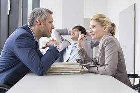 Colleagues having a positive disagreement discussion in the office, smiling.