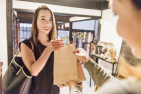 Young Japanese Woman Smiles As She Finishes Shopping Transaction