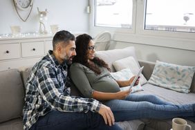 一个留着胡子的男人和一个怀孕的女人坐在沙发上，看着平板电脑上的预算＂>
          </noscript>
         </div>
        </div>
       </div>
       <div class=