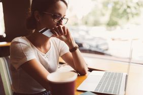 Woman holding her credit card and looking concerned while sitting at her laptop after filing a credit report dispute.