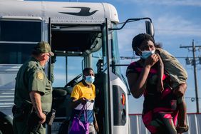 2021年9月22日，德克萨斯州德尔里约热内卢，移民们在穿越里约热内卢格兰德河后，离开边境巡逻巴士，准备接受瓦尔佛得角人道主义联盟的接待。成千上万寻求庇护的移民，其中大部分来自海地，已经越过格兰德河进入美国。许多家庭住在国际大桥下的临时帐篷里，等待进入该系统。美国移民当局一直将一飞机一飞机的移民直接驱逐到海地，而其他人则越过格兰德河返回墨西哥。