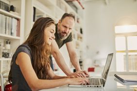 爸爸和女儿坐在办公室里用电脑做一些事情