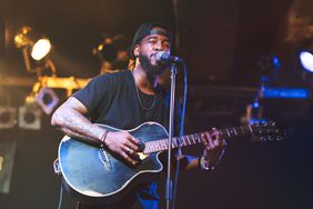 一个黑人在舞台上弹吉他唱歌