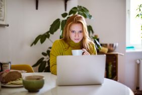 女人在家里喝咖啡和使用笔记本电脑