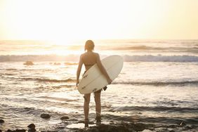 女子与冲浪板在岩石海滩