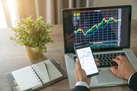 投资者在笔记本电脑和智能手机上分析股票市场图表。