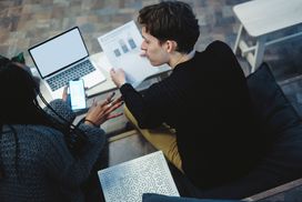 Young Couple Discusses Finances With Laptop, Charts and Phone