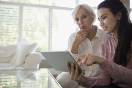 年轻的女人和爷爷看家庭保险覆盖平板电脑的现金重量＂width=