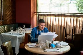 餐馆老板坐在桌子面前的笔记本电脑阅读文档