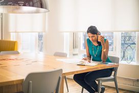 Woman at conference table reviews paperwork with cup in hand