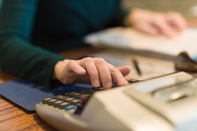 女性在她的办公桌上使用计算器作为一个注册会计师，簿记员，或会计。