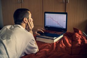 男人在卧室用笔记本电脑看股市崩盘