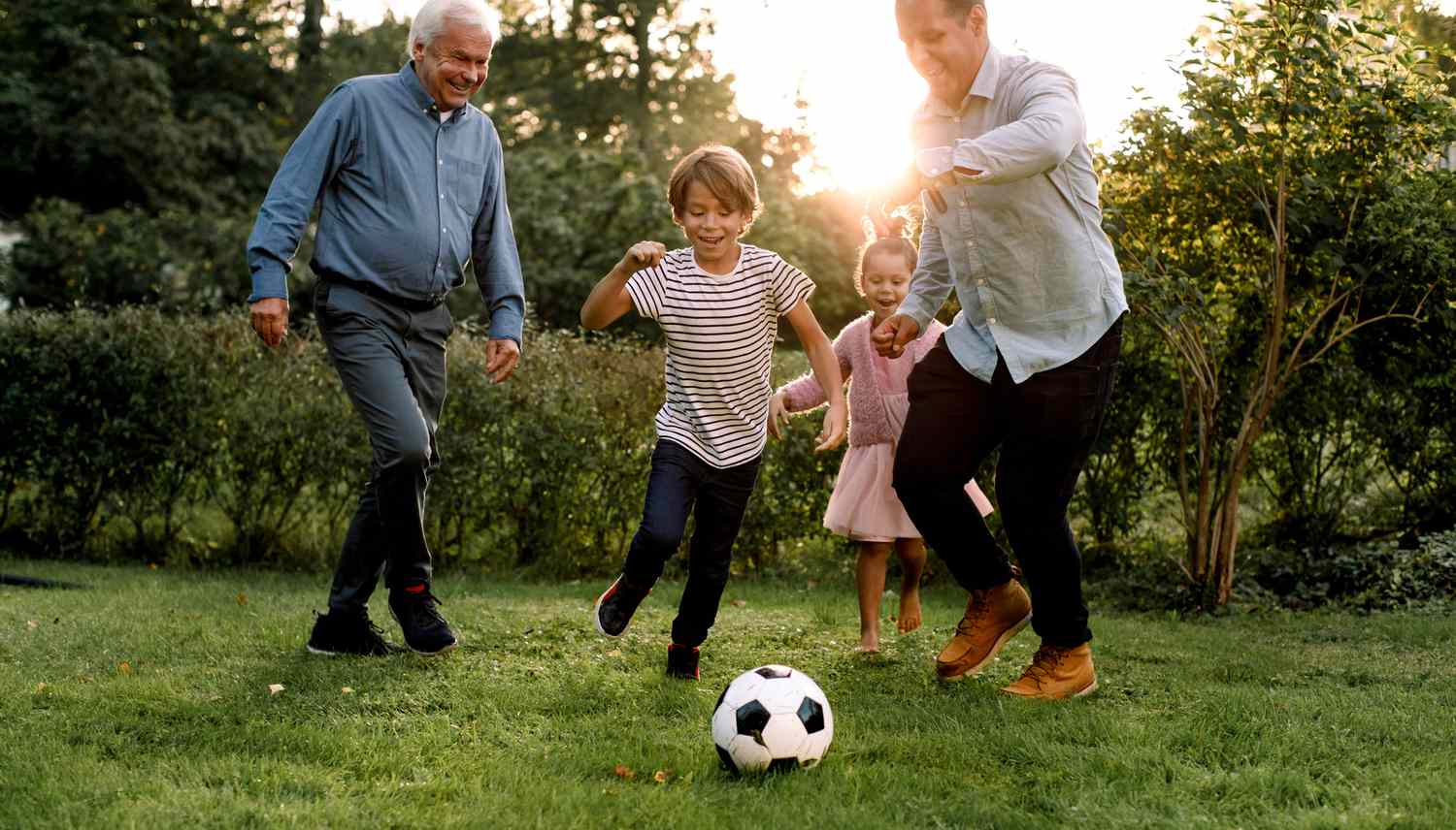 一个多代同堂的家庭在后院一起踢足球＂class=