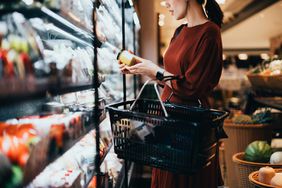 一名妇女在杂货店阅读罐子上的标签。