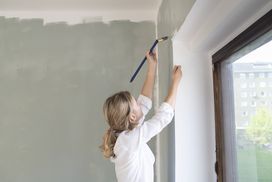 一个人在房子里粉刷墙壁。”width=