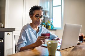 女人拿着信用卡，看着笔记本电脑。