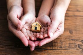 Close-up of woman and child holding model house in their hands