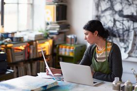 Young female artist in studio working on laptop