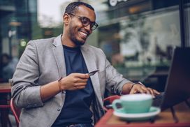 Man at cafe uses credit card to make online purchase